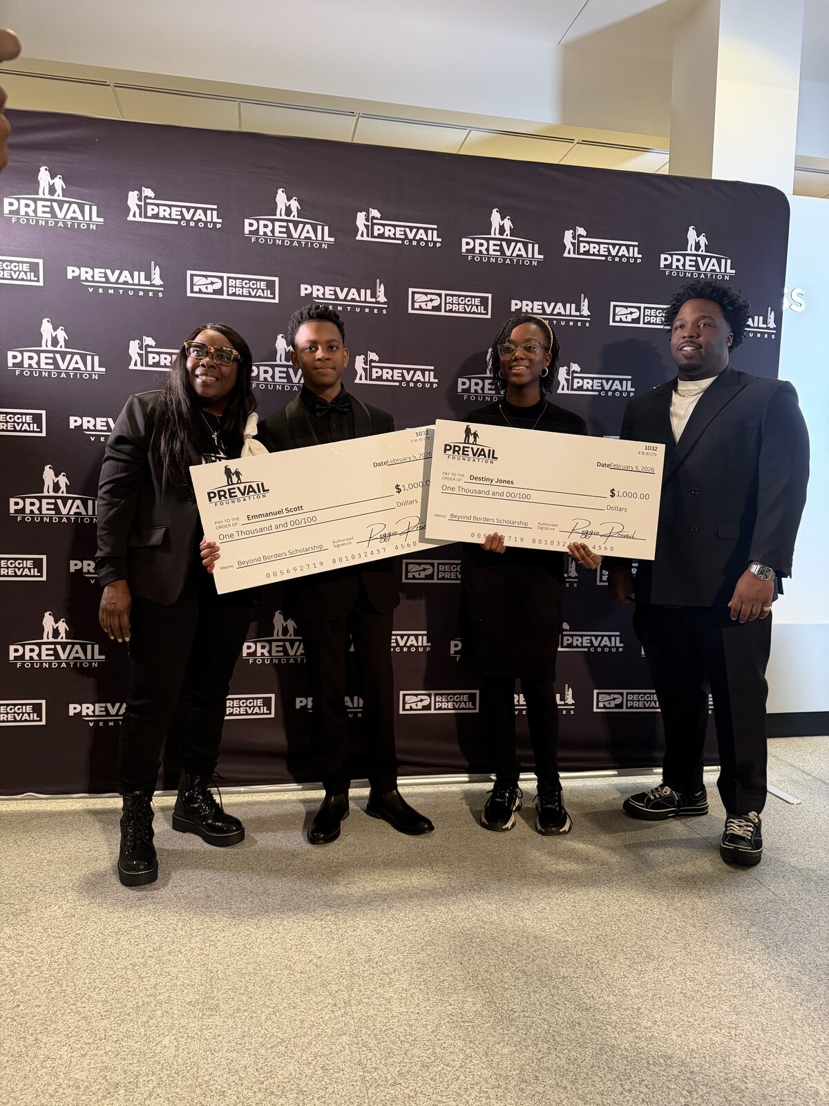 Emmanuel Scott and Destiny Jones holding their Beyond Borders Scholarship checks with Reggie Prevail
